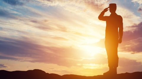 Comment les entreprises peuvent-elles s'inspirer de l'armée ? Un officier faisant un salut sur un fond de soleil couchant