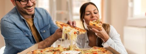 Quels sont les plats qui manquent le plus aux Français ? Un homme et une femme en train de manger une pizza