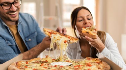 Un homme et une femme en train de manger une pizza