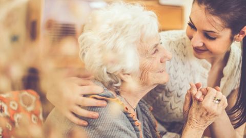 Une vieille femme avec une plus jeune femme en train de se tenir la main