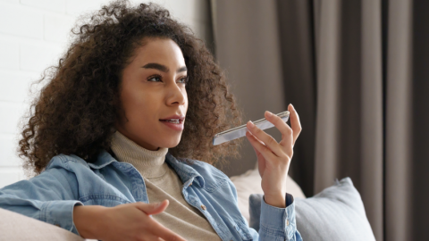 Femme noire parlant à l'assistant vocal de son téléphone