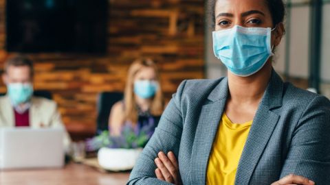 Une femme noire portant un masque chirurgical au bureau