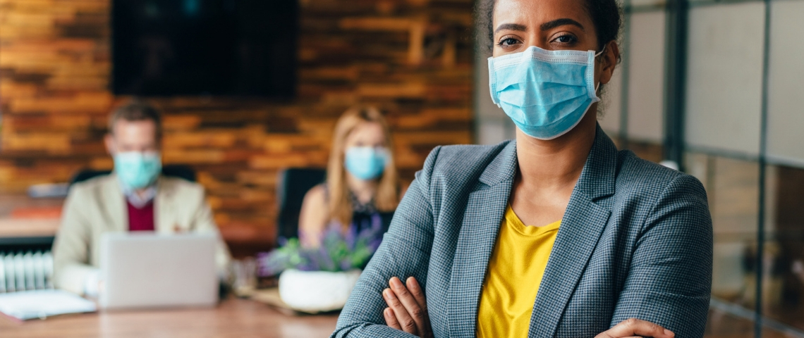 Quel est le rôle des chiefs covid officers ? Une femme noire portant un masque chirurgical au bureau