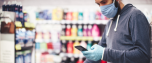 Homme portant un masque dans un supermarché en regardant son smartphone