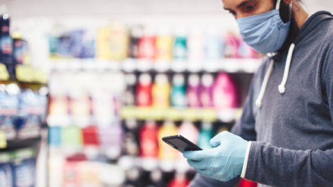 Homme portant un masque dans un supermarché en regardant son smartphone