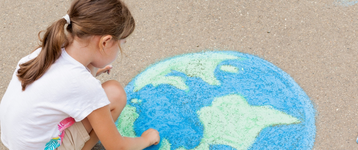 Unilever s'engage pour l'environnement Une petite fille en train de dessiner une terre à la craie au sol
