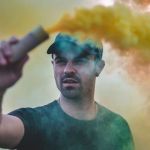 un homme blanc manifestant avec un fumigène