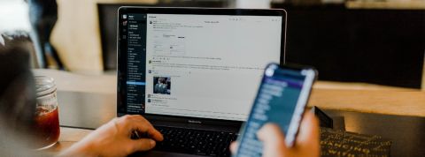Télétravail : la multiplication des outils numériques angoisse certains salariés Personne en train de regarder son téléphone portable et Slack sur son ordinateur en simultané