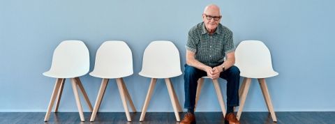 Quand les séniors restent sur leur (faim) de carrières… Un homme d'âge mur sur une chaise seul fond bleu