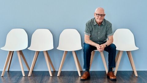 Un homme d'âge mur sur une chaise seul fond bleu