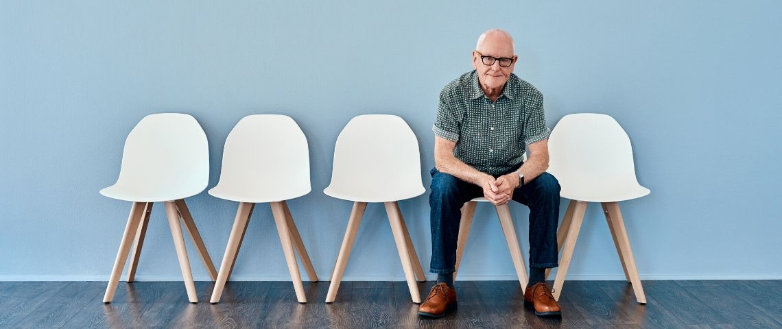 Quand les séniors restent sur leur (faim) de carrières… Un homme d'âge mur sur une chaise seul fond bleu