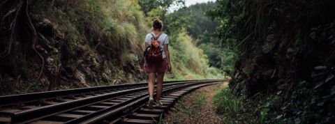 6 tech pour vagabonder de manière ludique Une jeune femme marche sur des rails de trains entourés de verdure