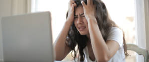 Une jeune femme asiatique en train de se prendre la tête entre les mains derrière son ordinateur