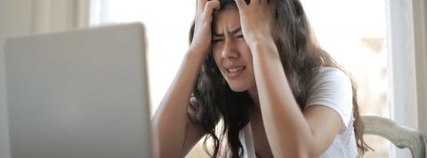 Les millennials sont dégoûtés du télétravail Une jeune femme asiatique en train de se prendre la tête entre les mains derrière son ordinateur