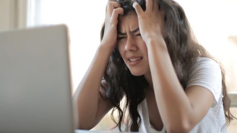 Une jeune femme asiatique en train de se prendre la tête entre les mains derrière son ordinateur