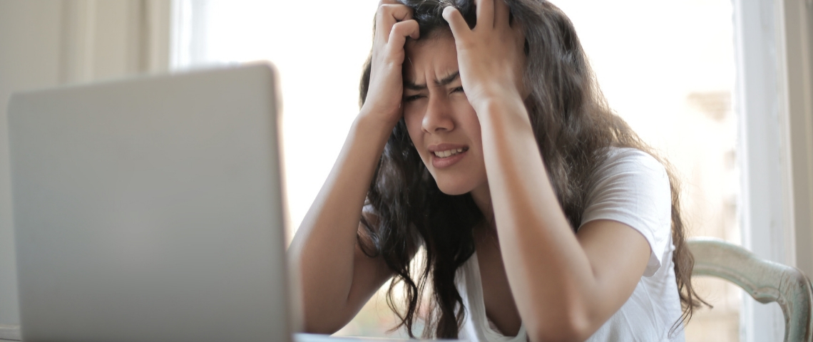 Les millennials sont dégoûtés du télétravail Une jeune femme asiatique en train de se prendre la tête entre les mains derrière son ordinateur