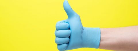 Comment affronter les crises Main pouce levé ganté et sur fond jaune