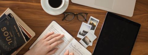 Comment bien communiquer ? Une femme écrivant dans un carnet avec une tasse de café