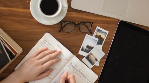 Comment bien communiquer ? Une femme écrivant dans un carnet avec une tasse de café