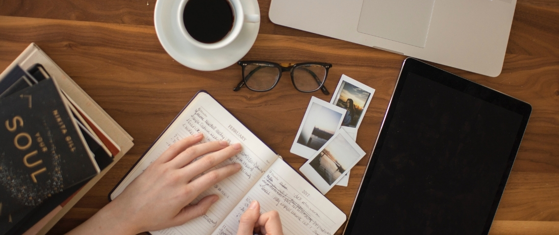 Comment bien communiquer ? Une femme écrivant dans un carnet avec une tasse de café