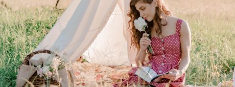 Qu'est-ce que le CottageCore ? Une femme qui pique nique dans un champs