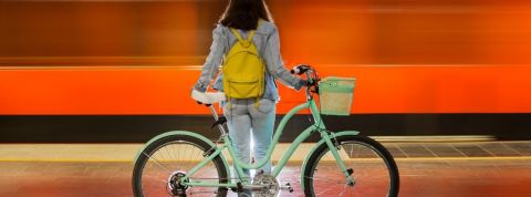 Les initiatives pour survivre à la crise Une femme de dos avec un vélo devant un fond rouge