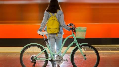 Les initiatives pour survivre à la crise Une femme de dos avec un vélo devant un fond rouge