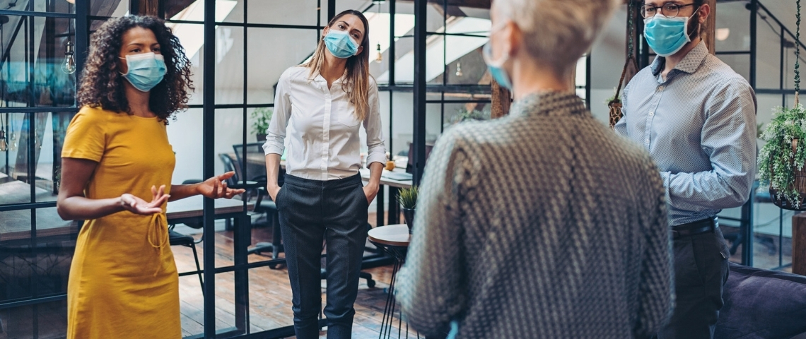 Quel est l'état d'esprit des dirigeants face à la crise Une femme en réunion avec ses employés, portant un masque, en entreprise