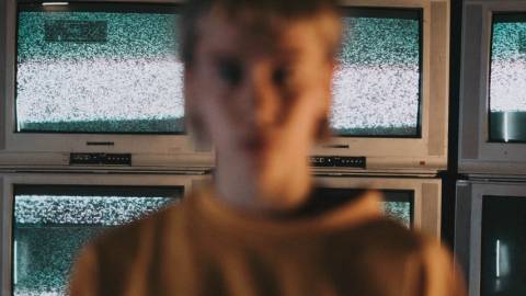 une femme floutée devant des écrans de télévision