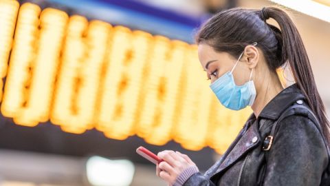 femme chinoise porte un masque et regarde son smartphone