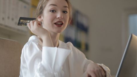 Une femme devant un écran d'ordinateur avec une carte bancaire