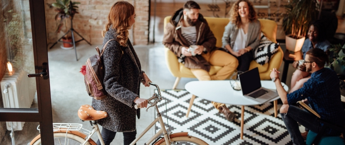 Great Place To Work dévoile son palmarès 2020 Une femme entrant dans son bureau avec son vélo