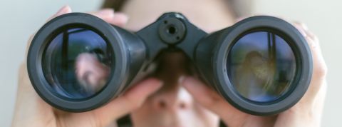 Quels sont les métiers du digital les plus demandés (et les mieux payés) Femme regardant dans des jumelles, gros plan.