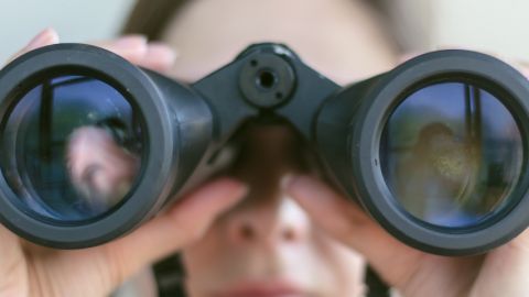 Femme regardant dans des jumelles, gros plan.