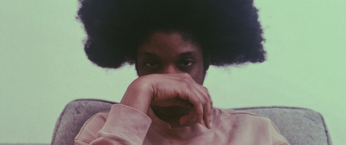 L'anxiété sociale est-elle le nouveau mal des ados ? Un jeune homme noir avec une coupe afro et sa main devant le visage