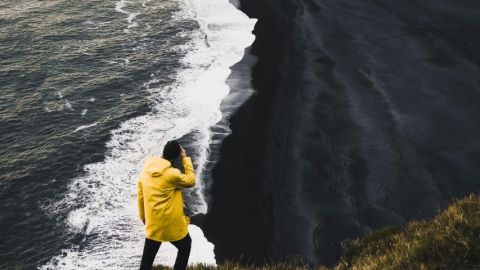 uUn homme en ciré jaune regarde une vague
