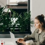Une femme qui travaille sur un ordinateur devant un miroir avec des plantes