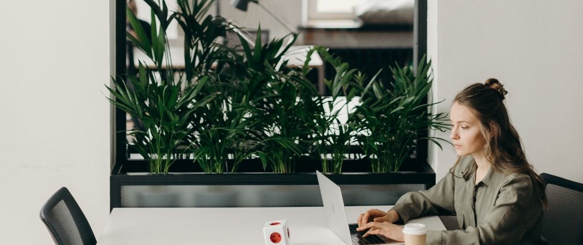 Il faut avoir un bureau Zoomable Une femme qui travaille sur un ordinateur devant un miroir avec des plantes