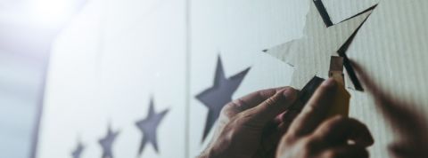 Fabrique de faux avis, pression constante... les dérives de la notation permanente à la loupe Homme en train de fixer une étoile en carton