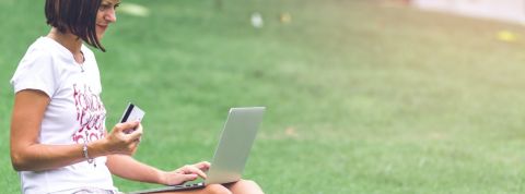 Amazon lance une plateforme écologique Une femme faisant ses courses sur son ordinateur portable, assise dans l'herbe