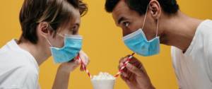 Un homme et une femme qui boivent un milkshake avec des masques chirurgicaux
