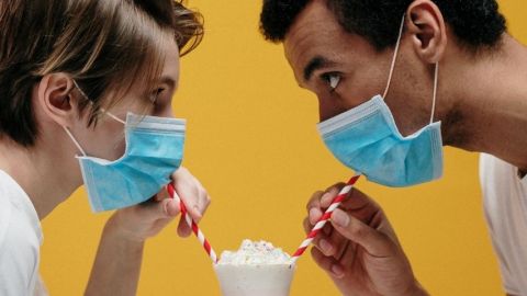 Un homme et une femme qui boivent un milkshake avec des masques chirurgicaux