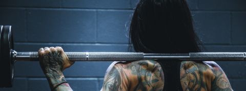 Anti-fragile : muscu is the new yoga Une femme tatouée de dos porte un haltère