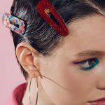 Une femme avec des barrettes colorées dans les cheveux sur fond rose