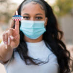 Une jeune femme tenant le sticker "I voted"