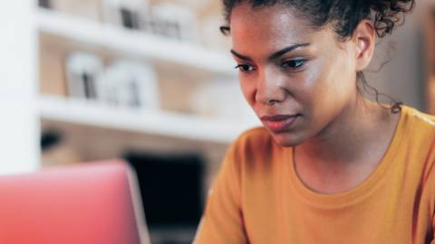 Une femme chez elle devant un ordinateur