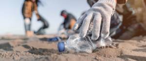 Personne en train de ramasser une bouteille en plastique sur la plage