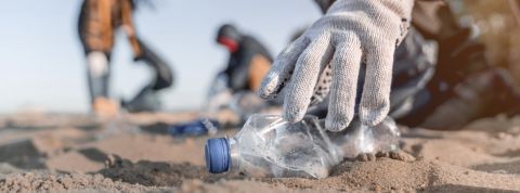 Personne en train de ramasser une bouteille en plastique sur la plage