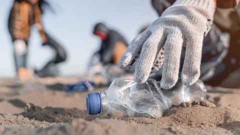 Personne en train de ramasser une bouteille en plastique sur la plage