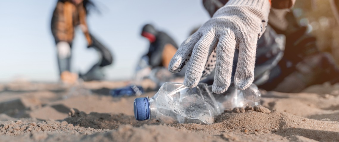 Personne en train de ramasser une bouteille en plastique sur la plage
